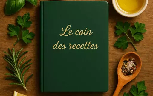 Carnet vert avec l’inscription dorée Le coin des recettes, entouré d’ingrédients frais et d’ustensiles de cuisine sur une table en bois.